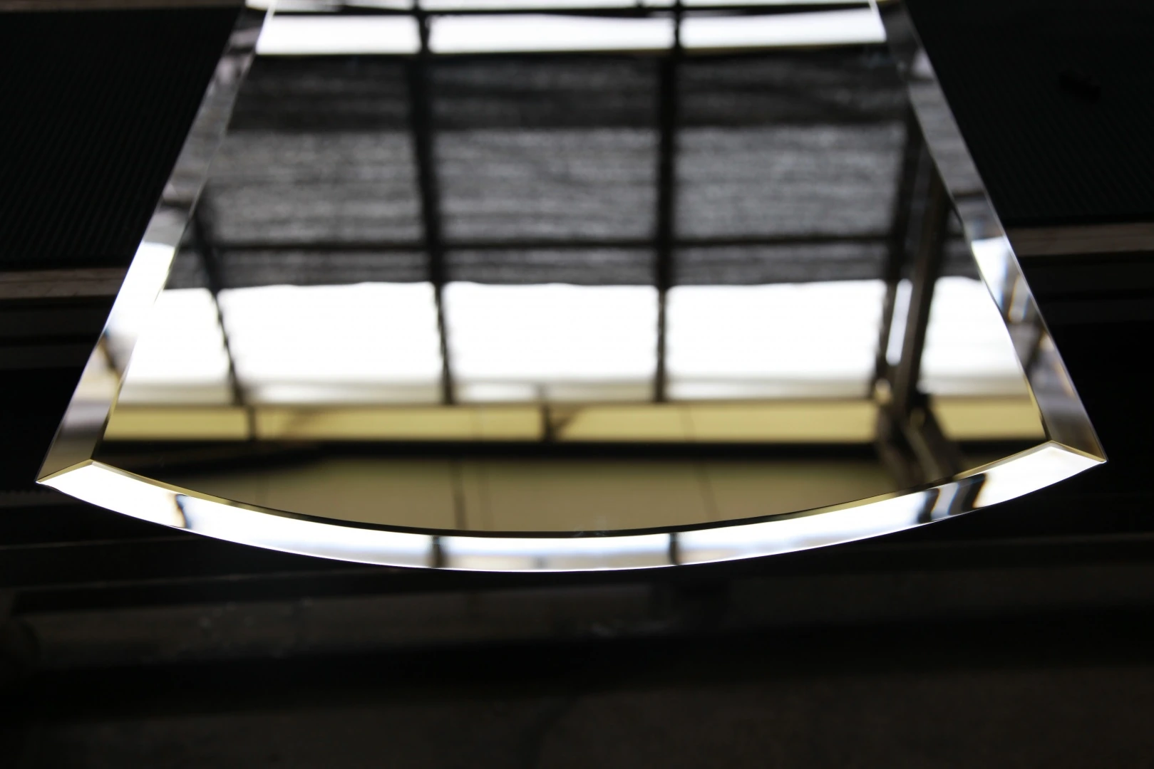 A light-catching polished bevel along the curved edge of a glass panel